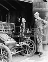 Man and woman looking at a wrecked car in the barn