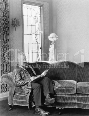 Man sitting on sofa and reading a book