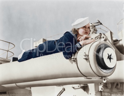 Woman in a sailors uniform lying on a cannon