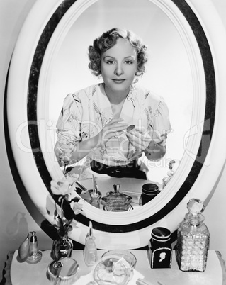 Woman sitting in front of her vanity looking into the mirror
