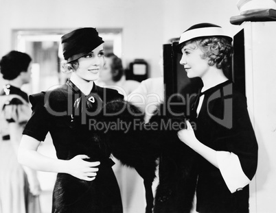 Two elegant women standing together in a department store