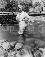 Woman with a fishing rod standing in the water