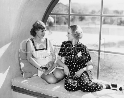 Two women in front of a window looking at each other