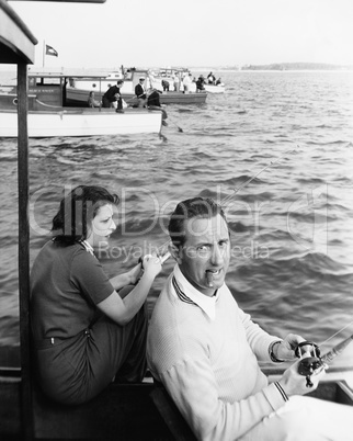 Man and woman sitting on a boat on a lake with their fishing rod