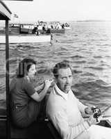 Man and woman sitting on a boat on a lake with their fishing rod