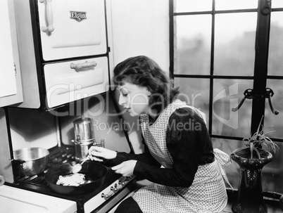 Woman in her kitchen preparing food on the stove