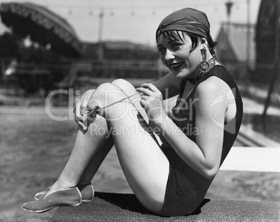 Portrait of a woman with a scarf around her head sitting next to the pool