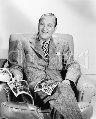 Man sitting on an armchair reading a magazine