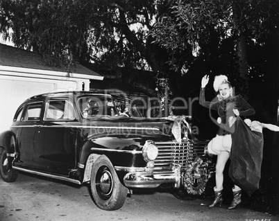 Woman standing in front of a car holding a bag of Christmas presents