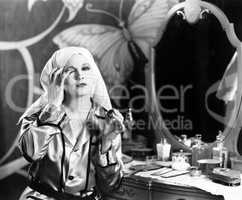 Woman sitting in front of her vanity and taking off her make up