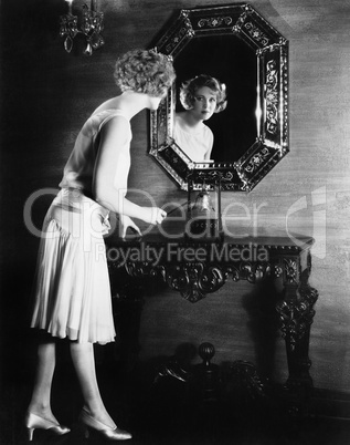 Woman looking into a mirror about to ring a bell
