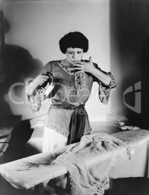 Woman with a finger in her mouth after she burned herself with an iron