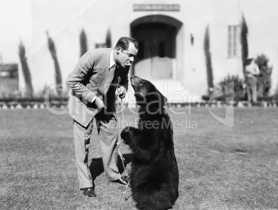 Man feeding a bear standing on his lawn