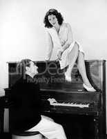 Woman singing on an upright piano with a friend playing