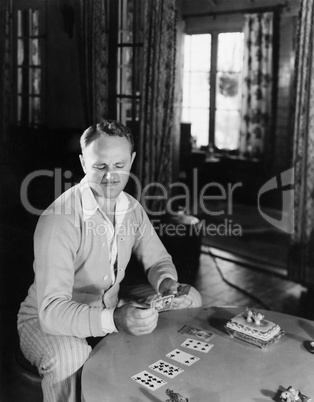 Man sitting in his living room playing cards