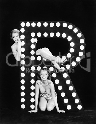 Two young women posing with the letter R
