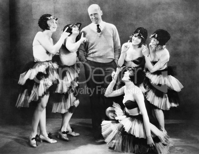 Five young women dancing around a man