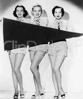 Portrait of three young women holding a banner and smiling