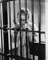 Young woman standing in a prison cell