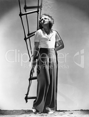Young woman holding a rope ladder and looking up