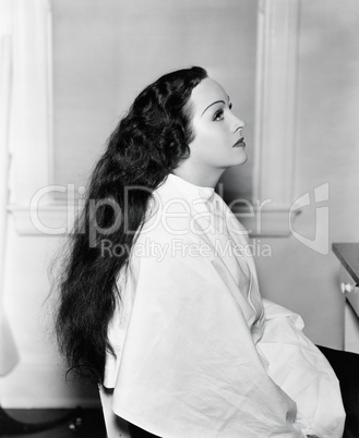 Profile of a young woman sitting in a hair salon with very long hair