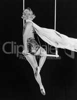Profile of a female circus performer performing on a trapeze bar