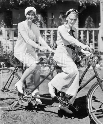 Portrait of two young women sitting on a tandem bicycle