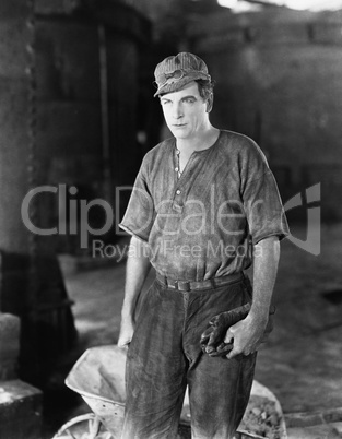 Construction worker standing near a wheelbarrow