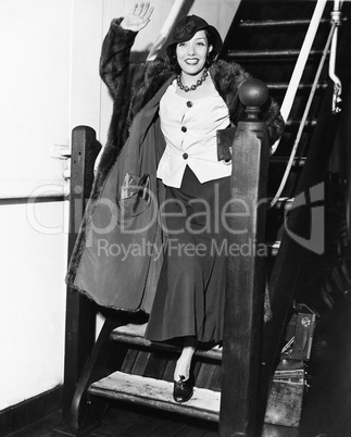 Young woman waving on a staircase and smiling