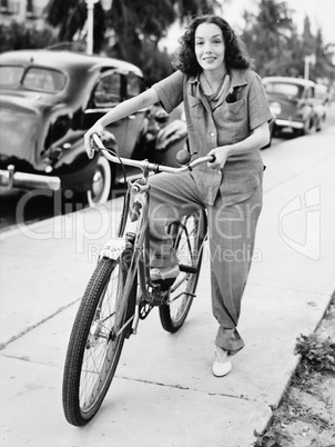 Portrait of a young woman holding a bicycle and smiling
