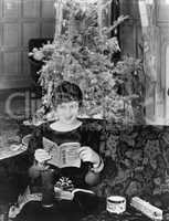 Young woman sitting on a couch with a Christmas tree in the background