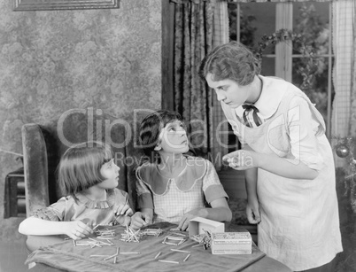 Woman scolding her two daughters for playing with matchsticks