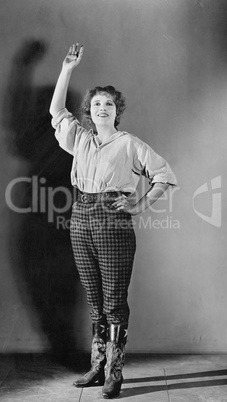 Young woman standing with her hand raised and smiling