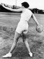 Rear view of a young woman throwing a discus