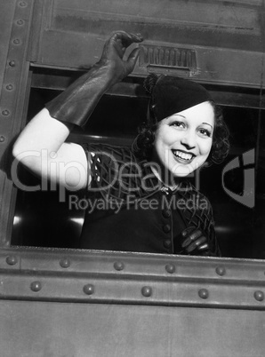 Low angle view of a young woman looking through the window of a train and smiling