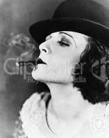 Portrait of a young woman with a hat smoking a cigar