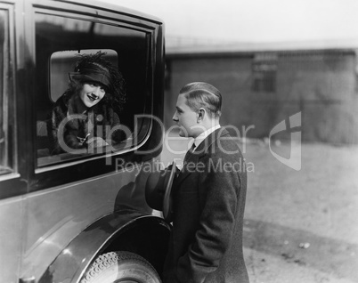 Young woman looking at a man through a car window