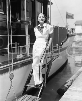 Portrait of a young woman standing on steps of a boat and smiling