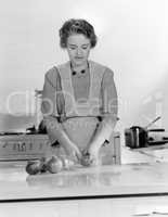 Woman peeling onions into a bowl in the kitchen