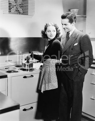 Profile of a young woman cooking food with a young man