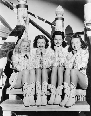 Portrait of four young women sitting on steps in western clothing