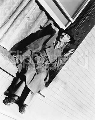 Young woman sitting on a window sill wearing men's clothing