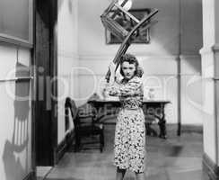 Young woman holding a chair above her head in anger