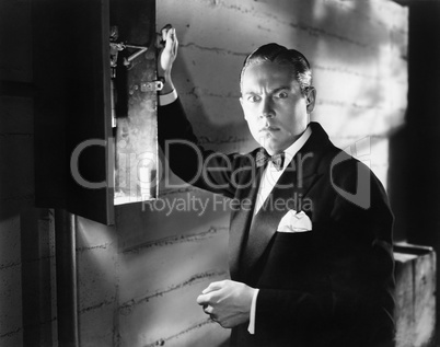 Man standing in front of a fuse box looking frightened