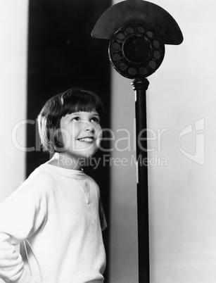 Profile of a young girl looking at a microphone and smiling