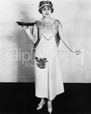 Woman in an apron holding a plate of food and smiling