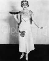 Woman in an apron holding a plate of food and smiling