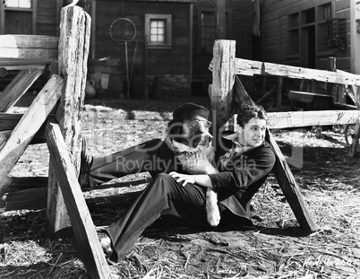 Young man sitting next to a fence with his dog