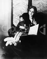 Woman sitting in an armchair with her puppet reading a book