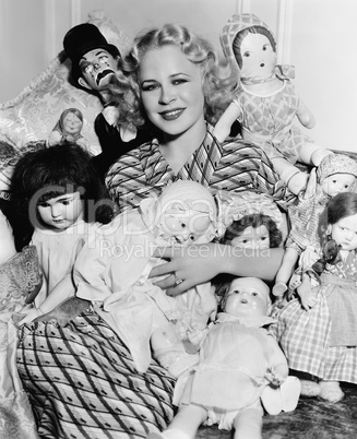 Portrait of a woman surrounded by dolls and smiling